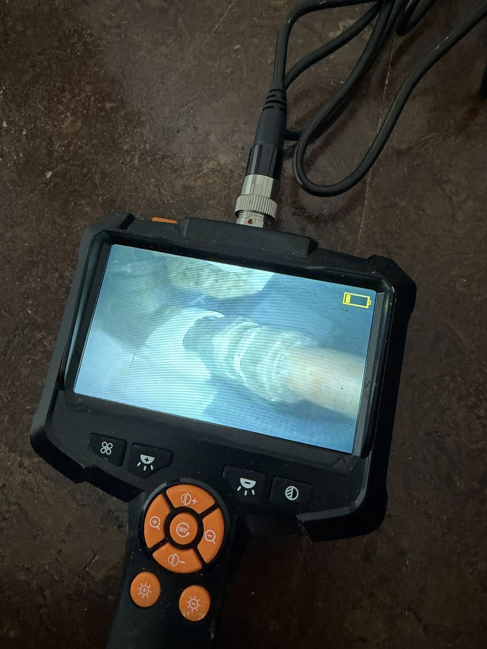 Borescope camera screen showing pipework inside a void